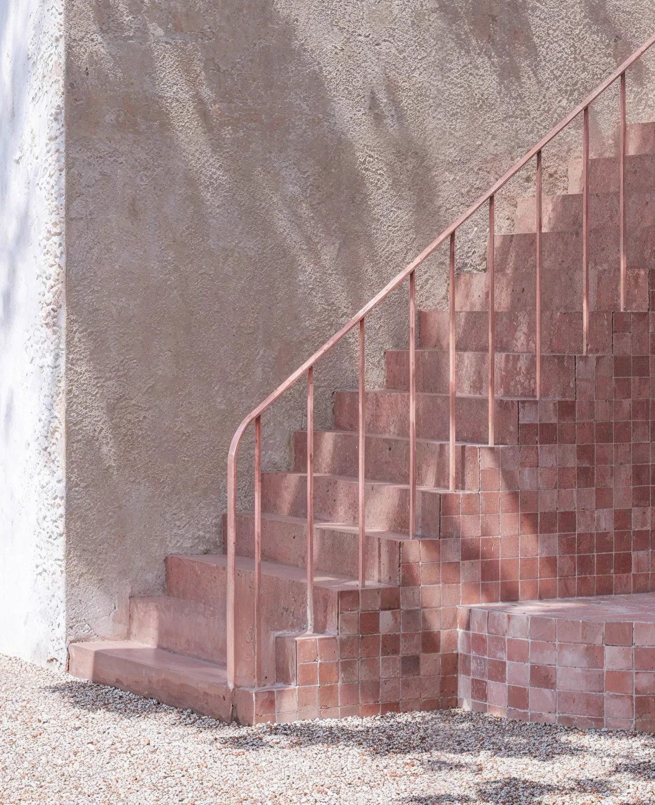 Escalier carrelé rose contre un mur enduit